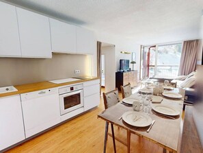 A modern kitchen with white cabinets, a wooden countertop, and a dining area with a table set for two. - Ski-in/ski-out apartment, exceptional view - 6 guests (Les Arcs)