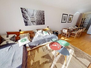 Un salon avec un canapé, un coin repas avec une table et des chaises, et un mur orné de tableaux.