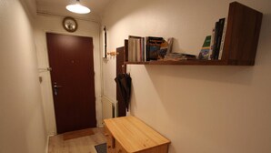 Käytävä, jossa on puinen penkki, ovi ja hylly täynnä kirjoja.