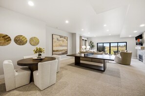 A modern living room with a dining area, a large painting, and a view through the windows. - Luxury 4BR | Free Ski Shuttle | Hot Tub | Deer Valley (Heber City)