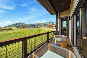 Un balcon donnant sur un paysage verdoyant et des montagnes.