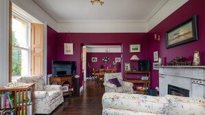 Ein Wohnzimmer mit Kamin, Fernseher und Essbereich im Hintergrund.