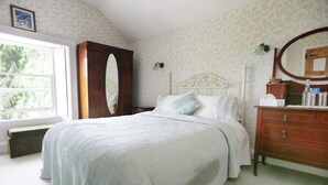 Ein Schlafzimmer mit Bett, Schminktisch und Fenster.