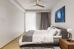 A modern bedroom with a bed, curtains, a painting, and a nightstand. - Laguna Beachside, 1BR • 200m to Bang Tao Beach (Choeng Thale)