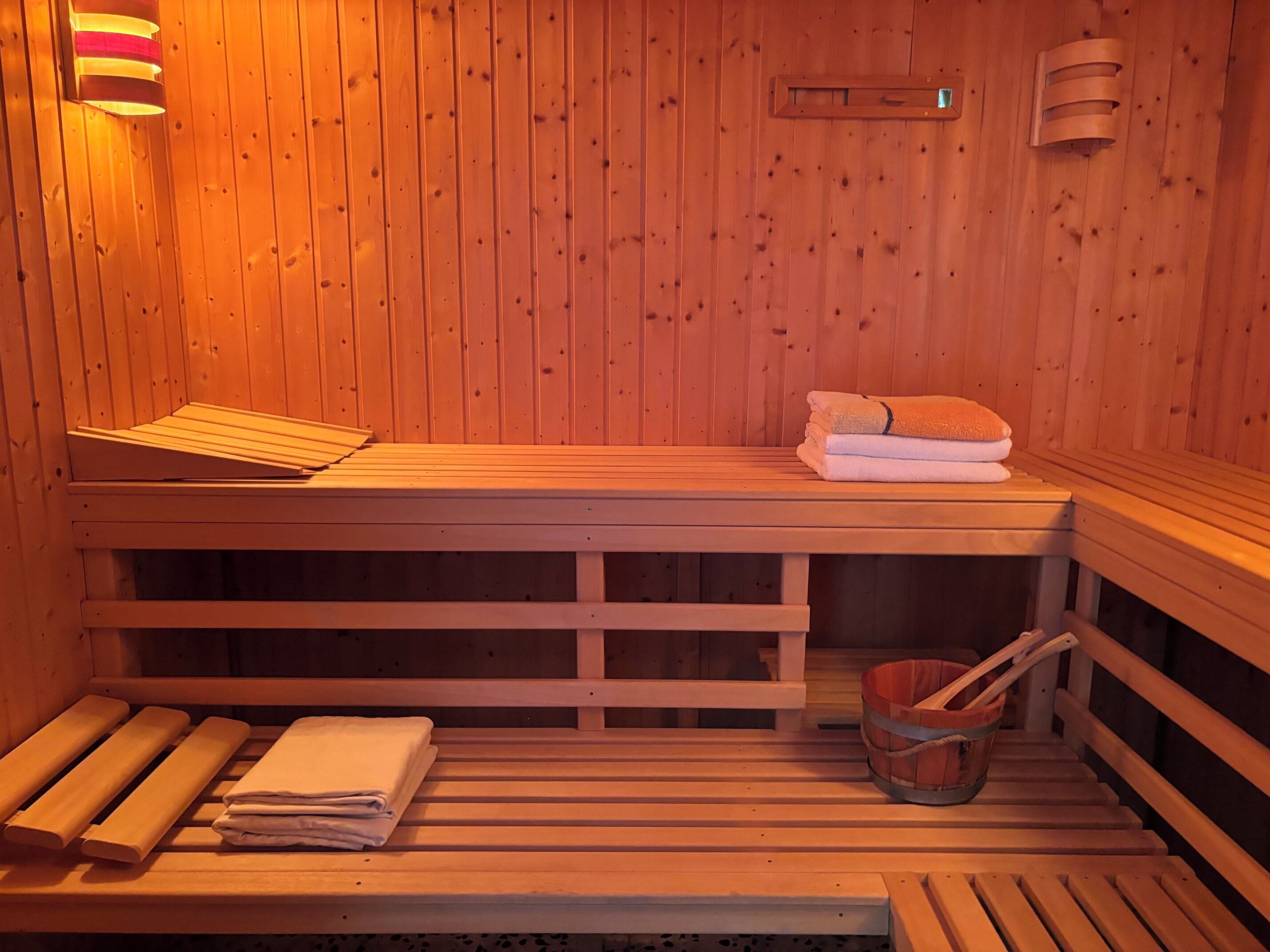 Eine Holzsauna mit Bänken, Handtüchern und einem Eimer.