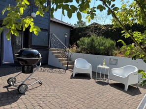 A patio area with a barbecue grill, white chairs, and a small table with glasses. - Vacation Rental with Sauna & Terrace in Hürtgenwald (Hürtgenwald)