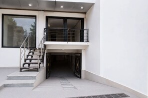 A building entrance with a staircase leading to a balcony.