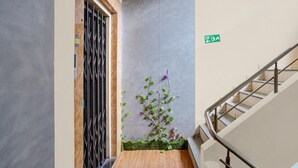 Una escalera con barandilla de metal, un letrero de salida de incendios y una pared cubierta de plantas trepadoras.