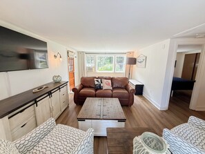 A living room with a brown leather sofa, a wooden coffee table, and patterned chairs. - Nautical three bedroom sleeping 6 in West Dennis! (West Dennis)