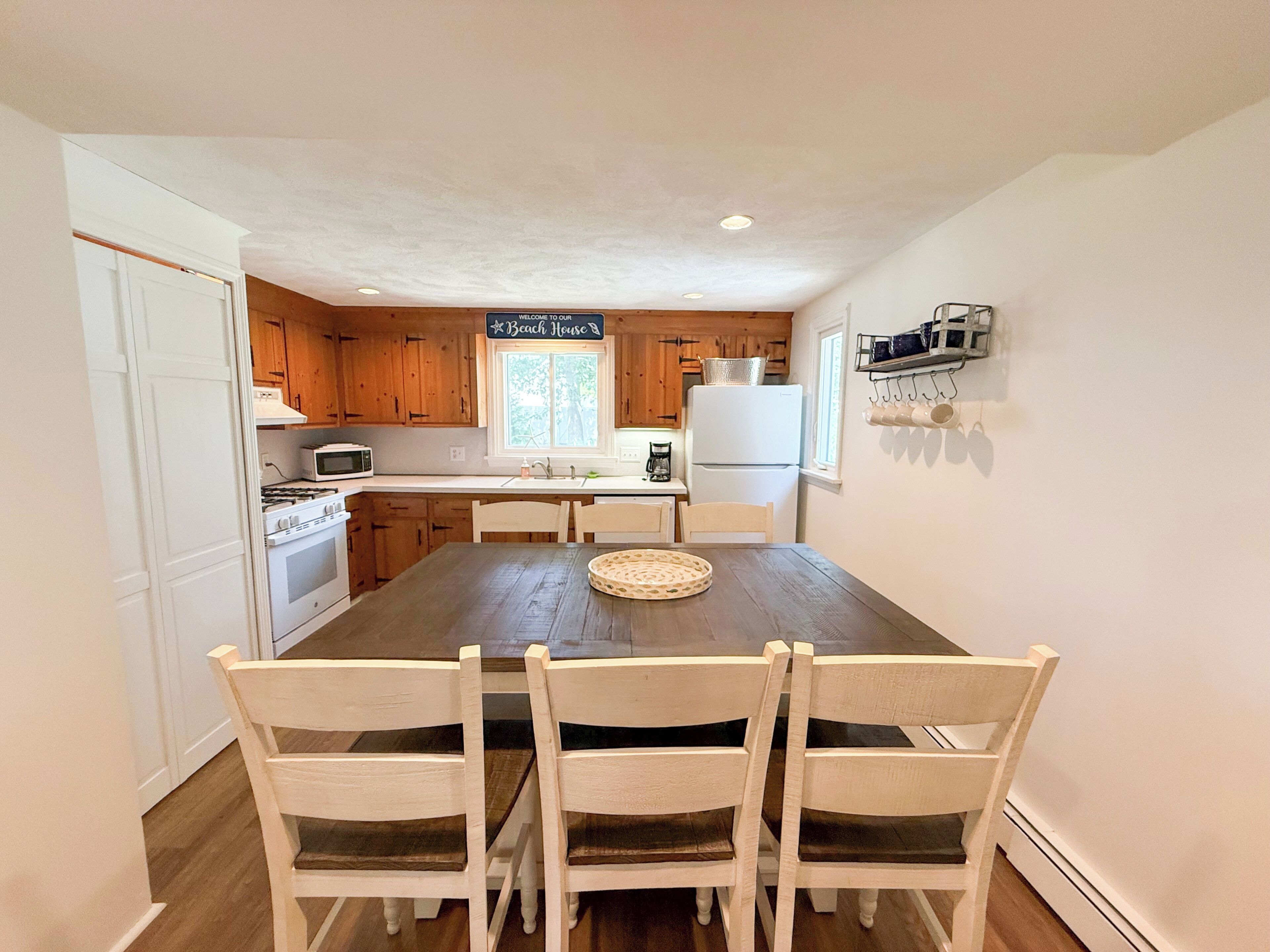 A kitchen with wooden cabinets, a white refrigerator, a stove, and a dining table with chairs.