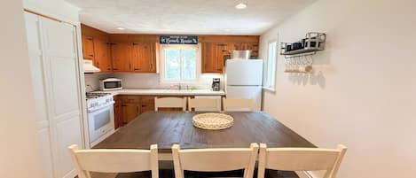 A kitchen with wooden cabinets, a white refrigerator, a stove, and a dining table with chairs.