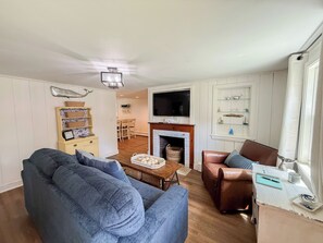 A living room with a sofa, a coffee table, a fireplace, and a television. - Nautical three bedroom sleeping 6 in West Dennis! (West Dennis)