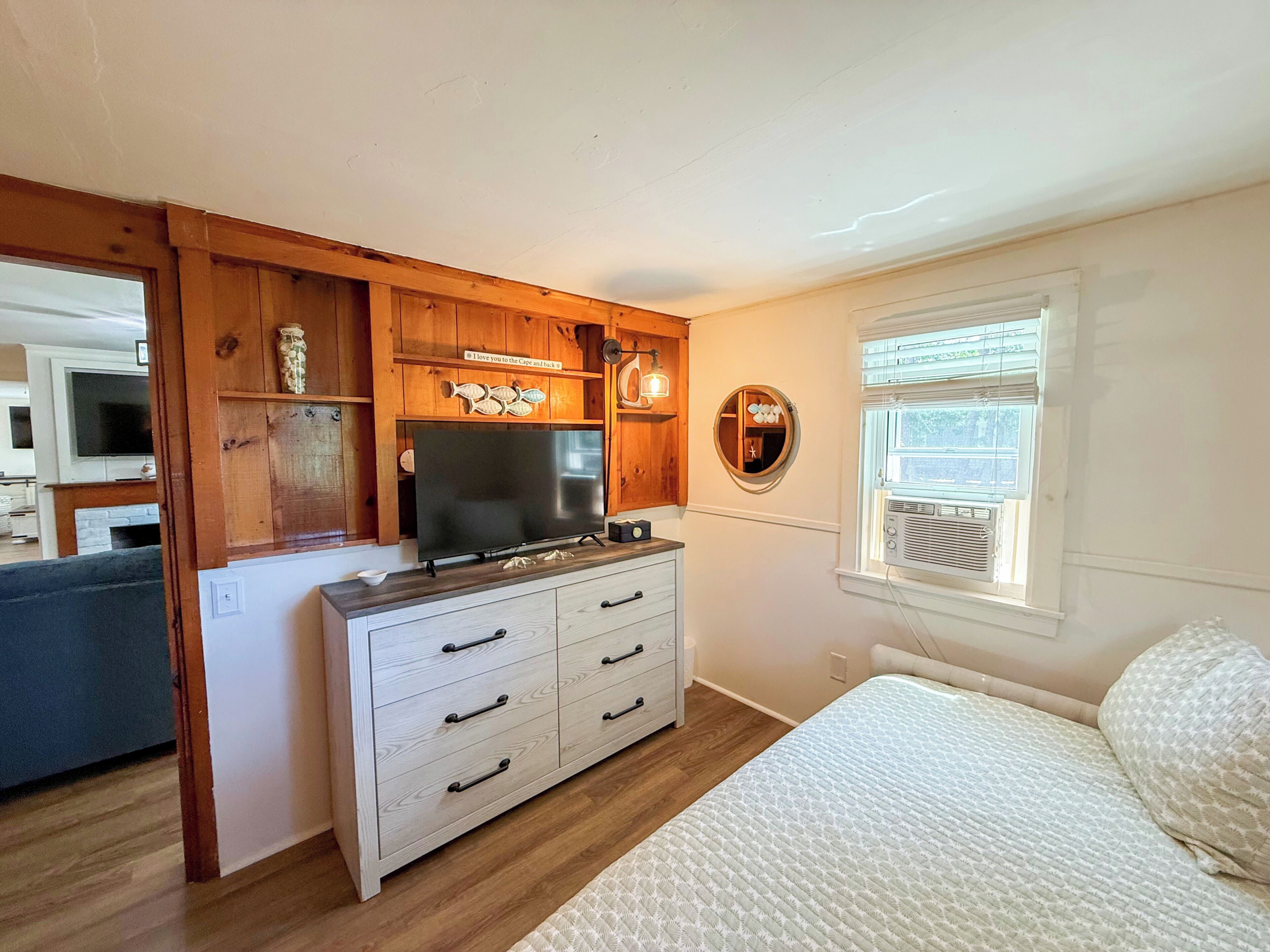 A bedroom with a bed, a dresser, a television, and a window with blinds.
