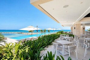 A resort pool area with lounge chairs and umbrellas, overlooking a clear blue ocean. - Ocean View | 5BR Staffed Resort Villa by Bocobay (St. Ann’s Bay)
