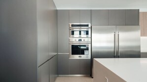Une cuisine moderne équipée d’appareils électroménagers en acier inoxydable, notamment un four encastré et un réfrigérateur.