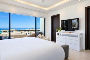 Une chambre moderne avec un grand lit, une télévision et une vue sur l’océan.