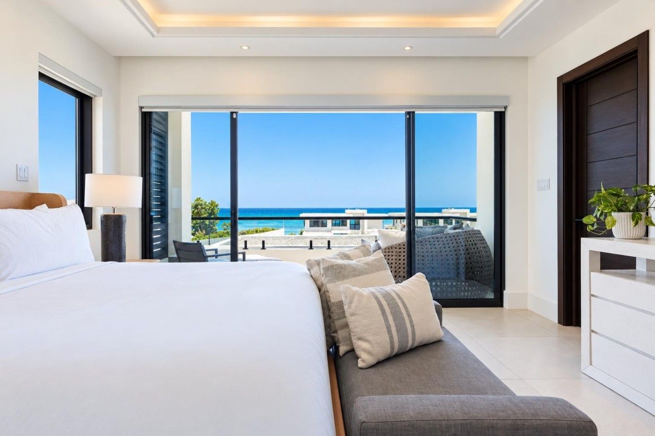 Una habitación de hotel con una cama grande, un área de descanso con cojines y vistas al océano.