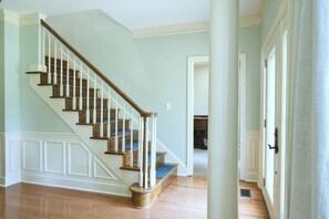 Een wenteltrap met houten treden en witte balusters, leidend naar een vloer met een blauw tapijt.