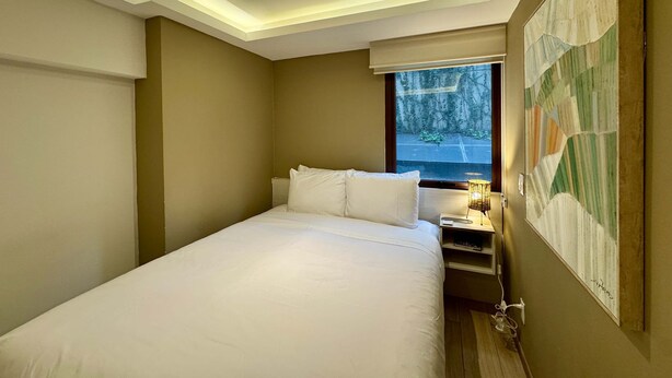 A bedroom with a bed, bedside table, lamp, and a painting on the wall. - w Enchanting 1BR in Prime Polanco (Mexico City)