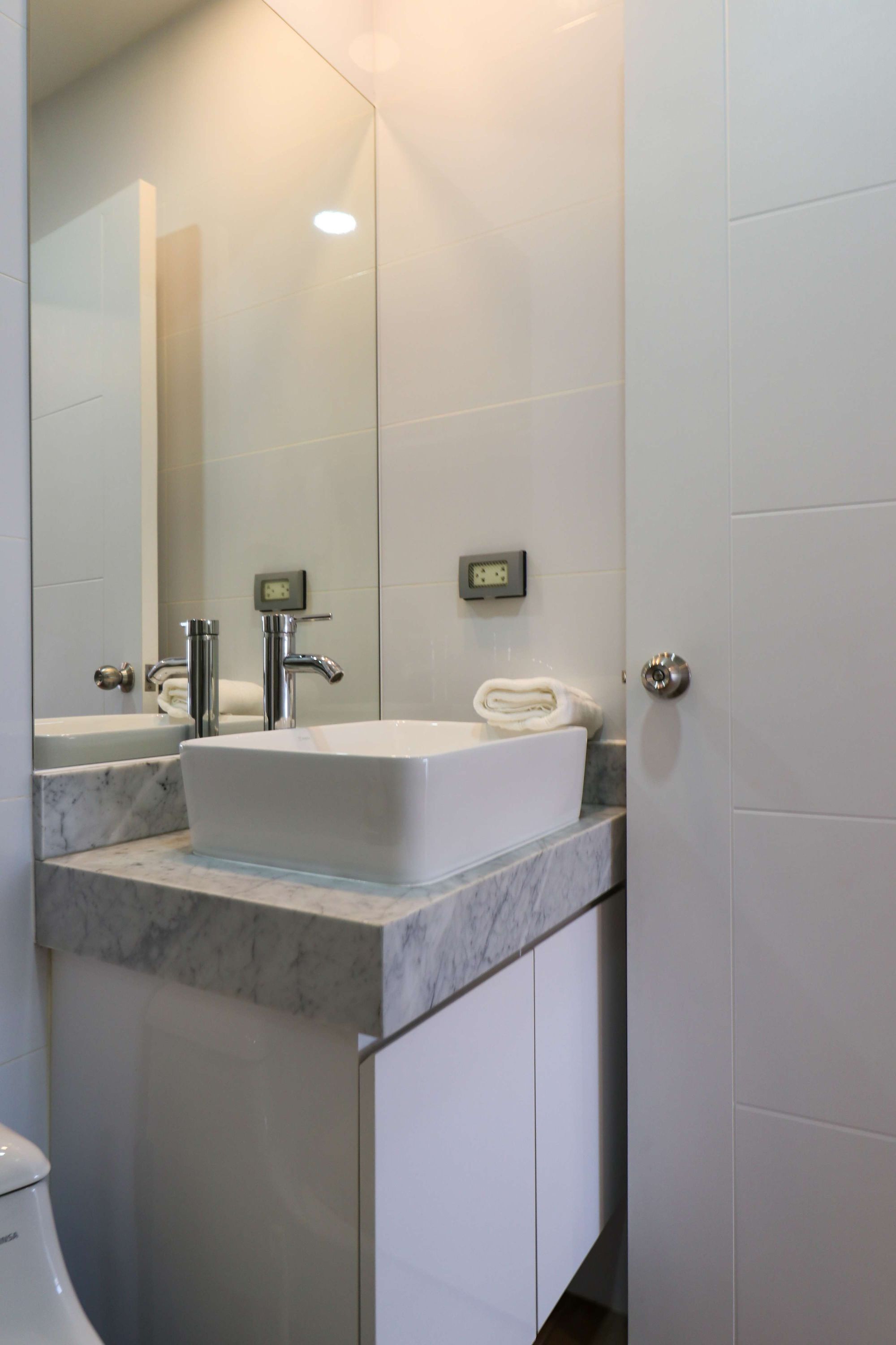 Ein modernes Badezimmer mit einem weißen Waschbecken, einem Spiegel und einer Toilette.