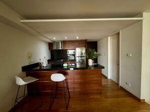 Eine moderne Küche mit Kochinsel, Barhocker und Holzboden.