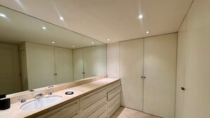 Ein modernes Badezimmer mit einem großen Spiegel, zwei Waschbecken und einem Waschtisch mit Schubladen.