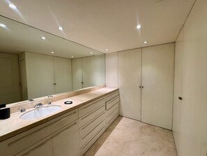 Ein modernes Badezimmer mit einem großen Spiegel, zwei Waschbecken und einem Waschtisch mit Schubladen.