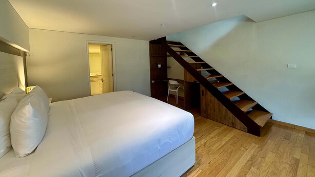 Ein Schlafzimmer mit einem Bett, einer Holztreppe und einer Tür zu einem Badezimmer.