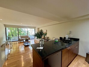 Eine moderne Küche mit einer großen Kochinsel, einem Essbereich inklusive Sofa und Blick durch eine Glastür.