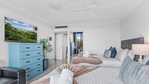Quarto de hotel moderno com cama, escrivaninha, cômoda e uma janela grande.