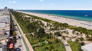 Un paisaje urbano costero con playa, palmeras y una carretera con vehículos.