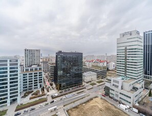 A modern urban area with high-rise buildings, a central glass skyscraper, and a busy road with vehicles. - Warsaw Home With City Views (Warsaw)