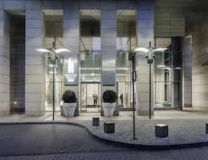 Ein modernes Gebäude mit Glasfassade, großen Kübelpflanzen und der Beschilderung 'Platinum Towers'.