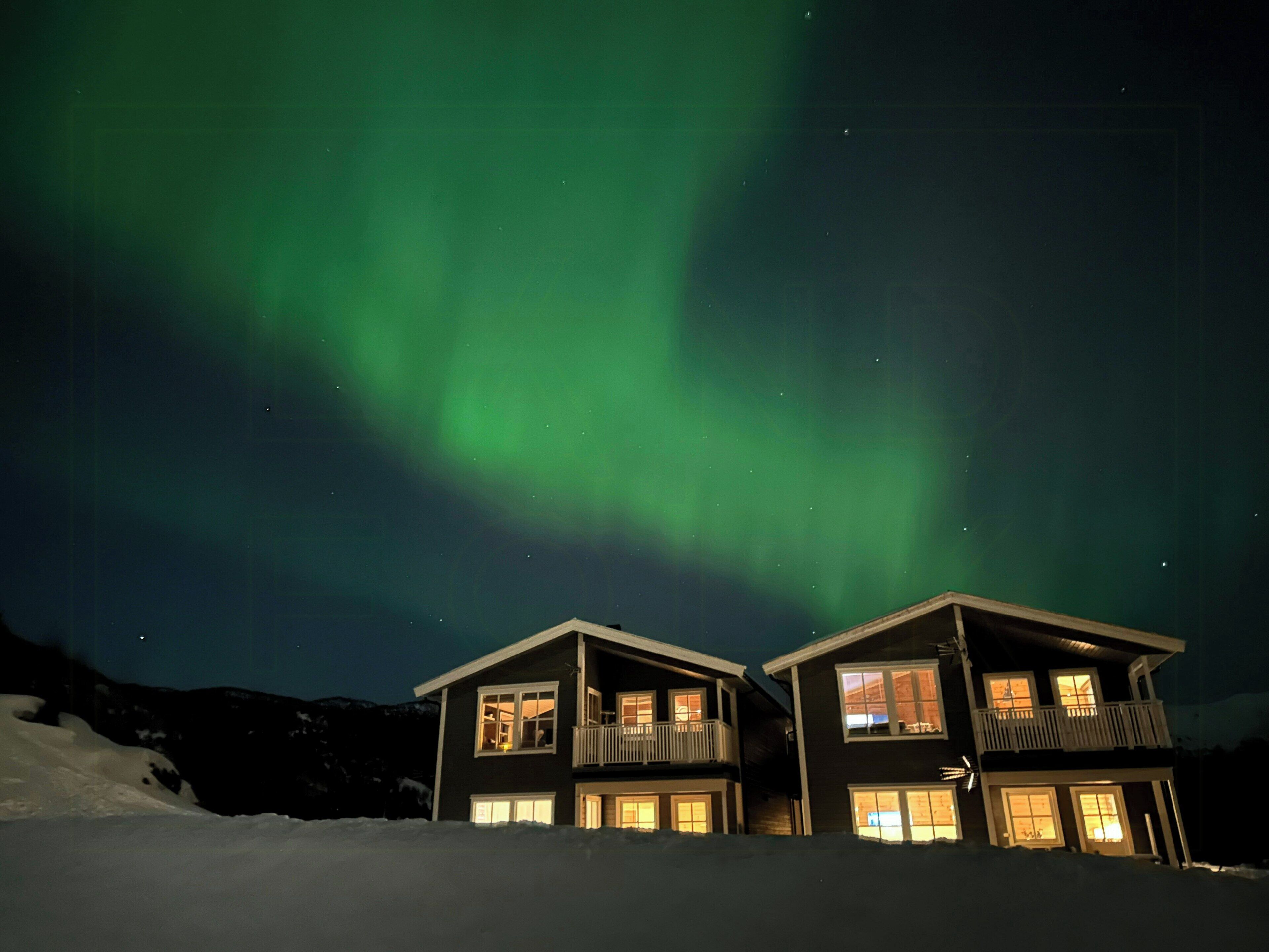 A two-story house with balconies, surrounded by snow, under a night sky with visible stars.