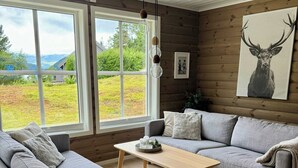 Un soggiorno moderno con un divano grigio, un tavolino in legno e un'ampia finestra con vista sull'esterno.