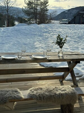 A wooden deck with a table set for a meal, overlooking a snowy landscape and a body of water. - Bright apartment in Kvasshaugen holiday park (Trøndelag)