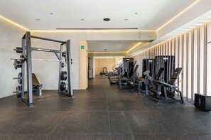 Une salle de sport moderne équipée de matériel de musculation, d’un banc et d’appareils de cardio.