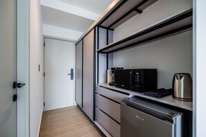 Eine moderne Küche mit eingebauter Mikrowelle, Kaffeemaschine und kompaktem Kühlschrank.
