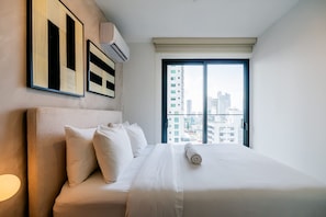 Ein Hotelzimmer mit einem großen Bett, Blick auf die Stadt und modernem Design.