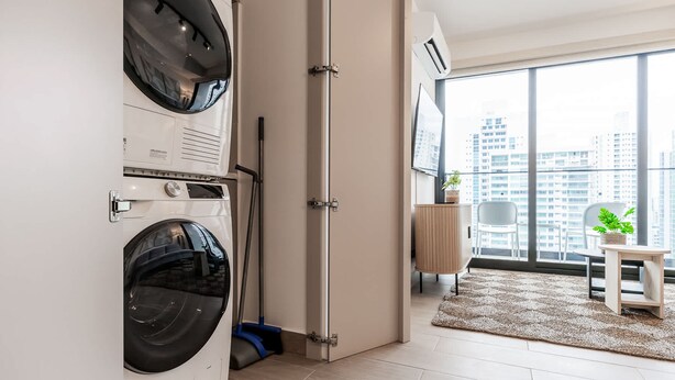 A modern apartment with a laundry area, a large window with a city view, and a small seating area with a plant. - w Elegant 2BR w Balcony AC in San Francisco (Panama City)