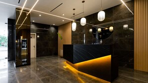 A modern reception area with a marble reception desk, pendant lighting, and a wooden accent wall. - w Elegant 2BR w Balcony AC in San Francisco (Panama City)