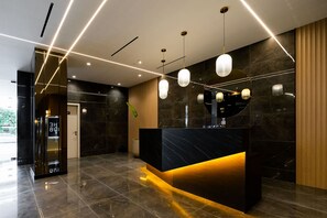 A modern reception area with a marble reception desk, pendant lighting, and a wooden accent wall. - w Elegant 2BR w Balcony AC in San Francisco (Panama City)