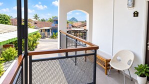 Ein Balkon mit Metallgeländer, einem weißen Stuhl und einem Blumentopf.