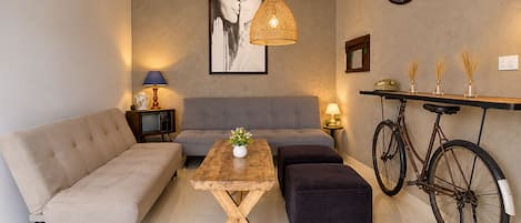 A modern living room with a sofa, a coffee table, a small ottoman, a television, and a bicycle.