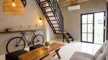 Un interior moderno con una escalera, una bicicleta, una mesa de madera y un sofá.