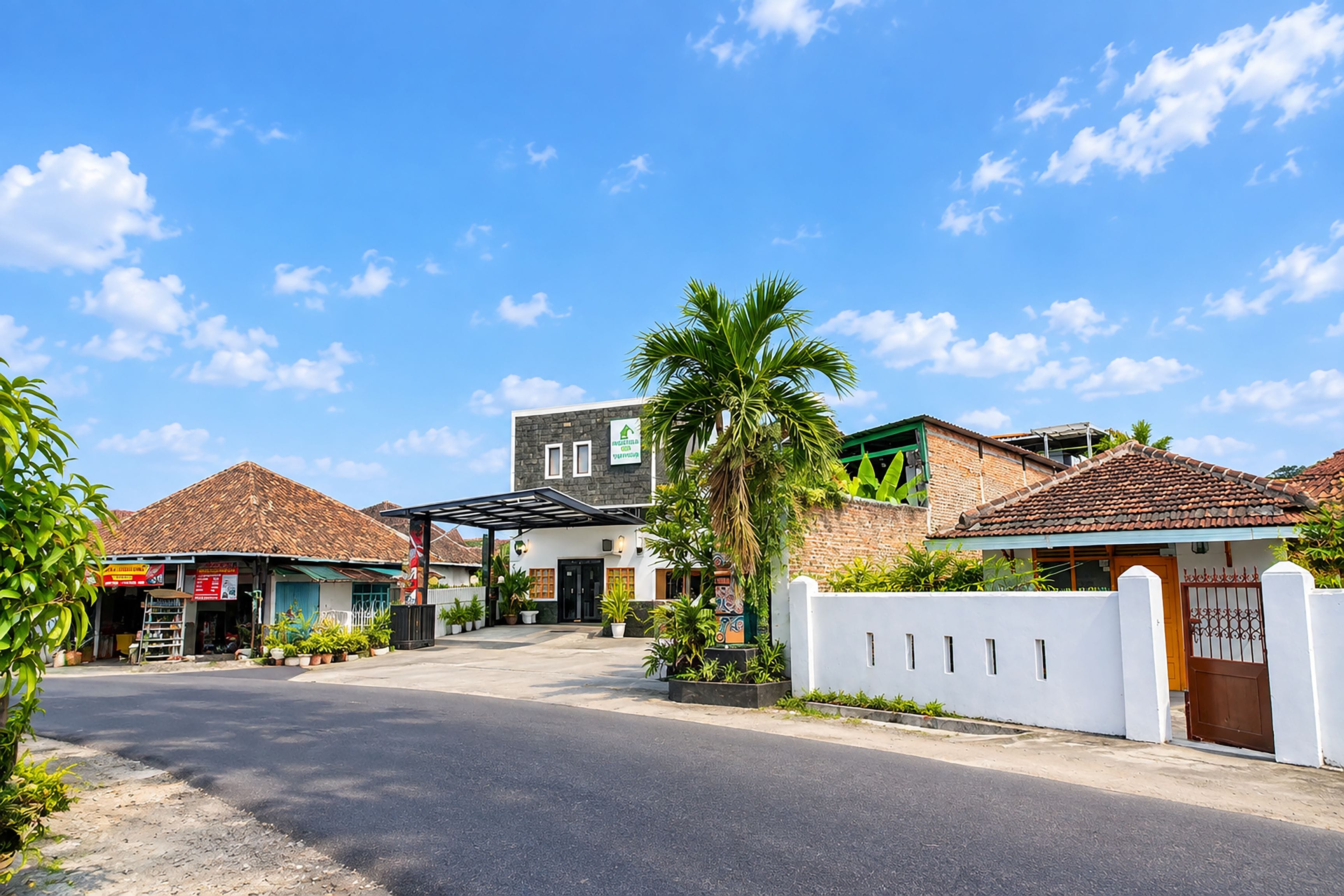 A residential street with houses, a gated entrance, and a clear sky.