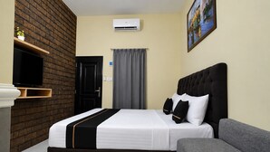 Ein Hotelzimmer mit Bett, einer Couch, einem Fernseher, einem Gemälde und einer Backsteinwand.