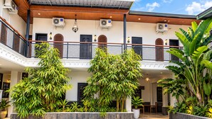 Ein Gebäude mit überdachtem Innenhof, mehreren Etagen und Außenbereichen mit Sitzgelegenheiten.