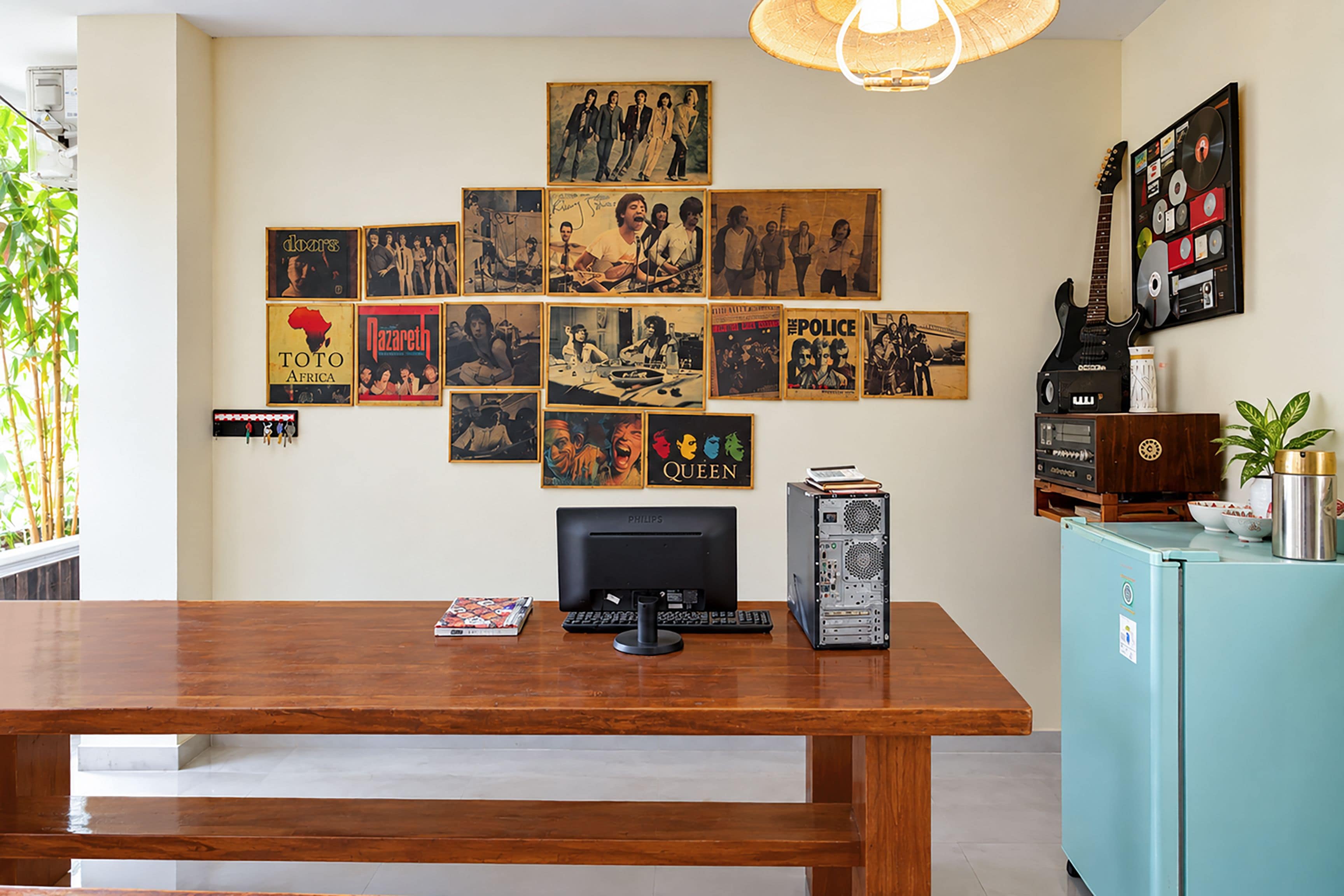 A room with a wooden desk, a computer, and a wall adorned with framed posters.