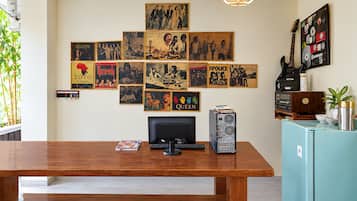 A room with a wooden desk, a computer, and a wall adorned with framed posters.
